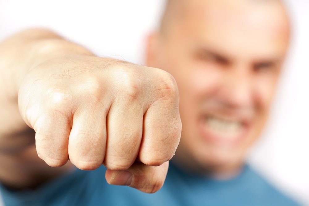 Strong built aggressive man punching towards the camera